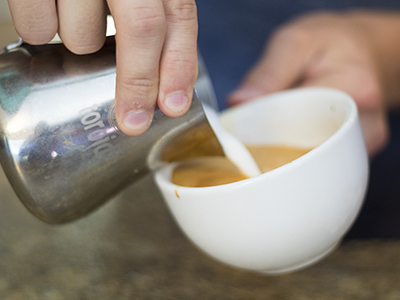 milk being poured in a coffee cup